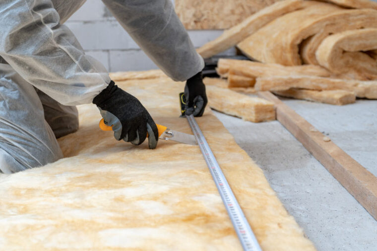 Professional workman installing thermal insulation rock wool under the roof